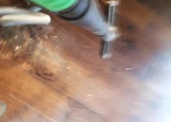 Close-up of a professional vacuum tool cleaning dust from wooden cabinet doors during refinishing in Newton MA