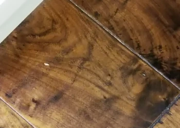 Close-up view of a custom kitchen cabinet wood surface showing natural grain and refinishing details