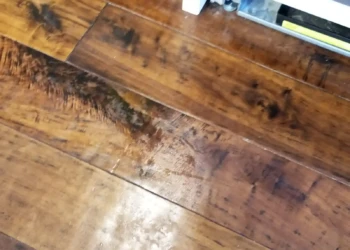 Close-up of a damaged wooden kitchen cabinet door panel with scratches and gouges during repair