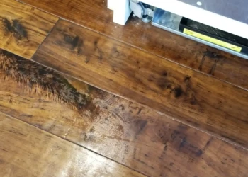 Close-up of wood cabinet surface with distinct grain and finish near a dishwasher base in a kitchen remodeling project