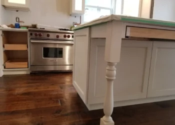 Close-up of custom refinished white kitchen cabinets and island with protective covering in Newton MA kitchen remodel