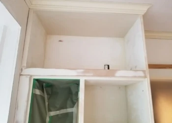 Upper custom kitchen cabinets with visible patches and bare wood areas during refinishing in Newton MA