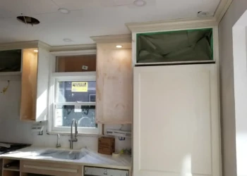 Partially refinished custom kitchen cabinets with some unfinished wood sections around window in Newton MA