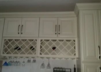 White kitchen cabinets with wine rack and hanging glass holders after refinishing in Reading MA
