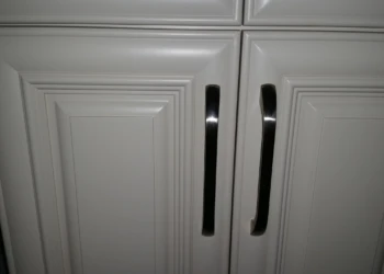 Close-up of white painted cabinet doors with black metal handles showing clean finishing details