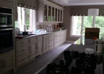 Refinished kitchen cabinets with glass fronts and classic hardware in a bright Reading Massachusetts kitchen