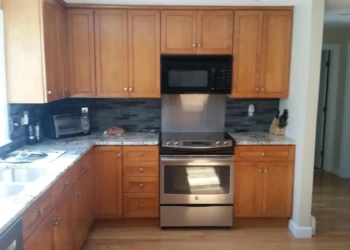 Finished cherry wood kitchen cabinets with stainless steel stove and gray tile backsplash in Sudbury, MA kitchen