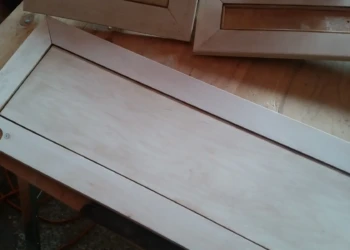 Close-up of refurnished cherry wood cabinet doors laid out on wooden work surface in Sudbury MA