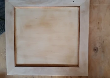 Sanded wooden cabinet door set on a workbench, prepared for cabinet refinishing in Sudbury MA