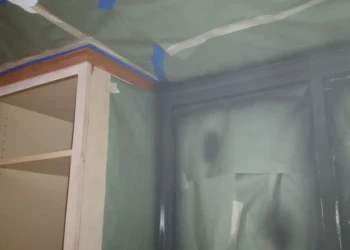 Partially painted kitchen cabinets with some surfaces masked off during cabinet refinishing in Sudbury MA