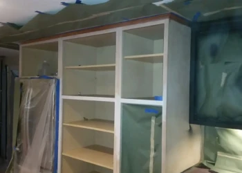 Unfinished kitchen cabinet frames prepared for refinishing in Sudbury MA, showing sanding and masking