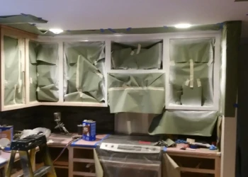 Kitchen upper cabinets in Sudbury MA covered with masking paper and tape for refinishing preparation