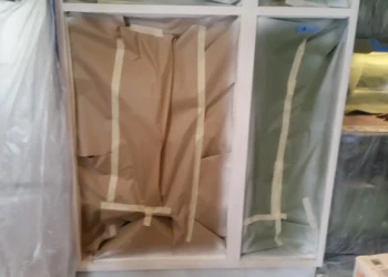 Kitchen cabinets prepared with masking paper and tape for cabinet refinishing in Sudbury MA