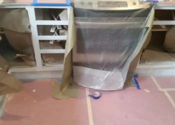 Kitchen cabinets masked and protected with paper and plastic during cabinet refinishing in Sudbury MA