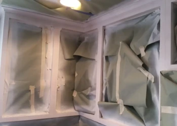 Kitchen cabinets in Sudbury MA covered with masking paper and tape during refinishing preparation