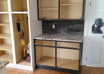 Partially refinished kitchen cabinets with dark painted frames and granite countertop in Sudbury MA kitchen