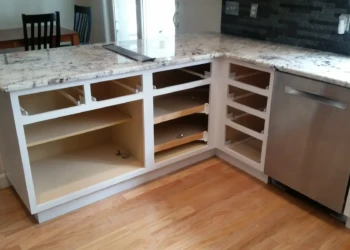 Kitchen cabinetry without doors and drawers beneath granite countertop, showing prep stage for cabinet refinishing in Sudbury MA