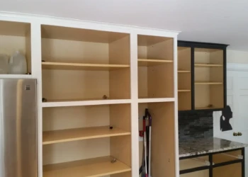 Kitchen cabinets showing two-tone refinishing with natural cherry wood interiors and black frames in a Sudbury MA kitchen