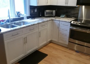 White kitchen cabinets with metal handles, granite countertops, and stainless steel appliances in a Sudbury MA kitchen