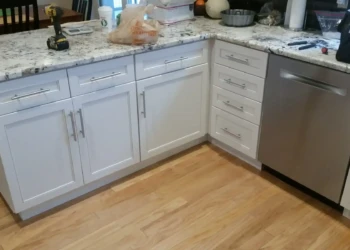 White kitchen cabinets with sleek silver handles and granite countertops in a Sudbury MA kitchen