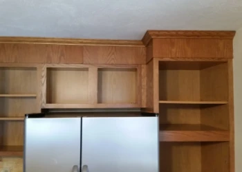 Wood finished kitchen cabinets without doors around a stainless steel refrigerator in Westford, MA