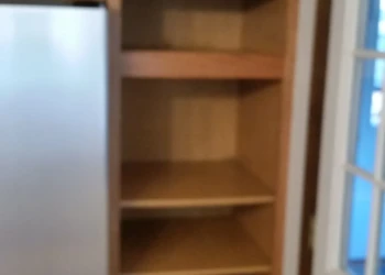 Tall wood cabinet with multiple empty shelves next to a refrigerator inside a Westford kitchen
