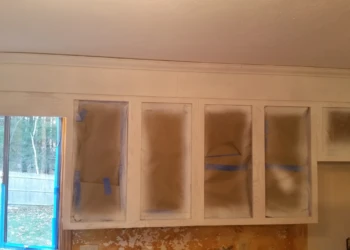 Kitchen cabinets in Westford being masked with paper and tape for cabinet refinishing painting
