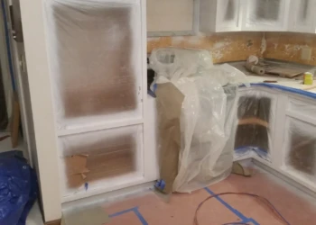 Kitchen cabinets masked with protective plastic and tape during cabinet refinishing painting in Westford MA