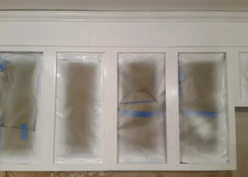 Kitchen cabinet doors prepped with protective paper and masking tape for cabinet refinishing painting in Westford MA