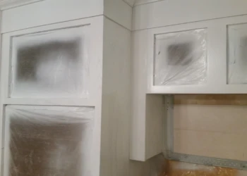 Kitchen cabinets covered with protective plastic during cabinet refinishing painting in Westford MA