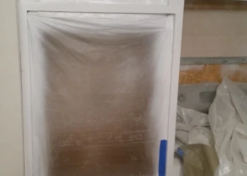 Cabinet surfaces covered with protective plastic sheeting during cabinet refinishing painting in Westford MA