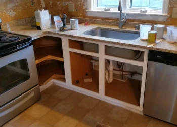 Kitchen countertop and sink area with cabinet doors and drawers removed showing unfinished cabinet boxes in Westford MA kitchen