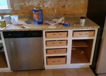 Kitchen cabinets in Westford MA mid refinishing with drawers removed and tools on granite countertop