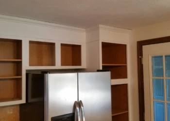 Open kitchen cabinets with white frames and natural wood interiors around a stainless steel refrigerator in Westford kitchen