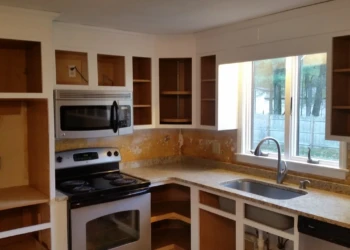 Unfinished kitchen cabinets with open shelves and no doors around a stainless steel stove and sink in Westford MA kitchen