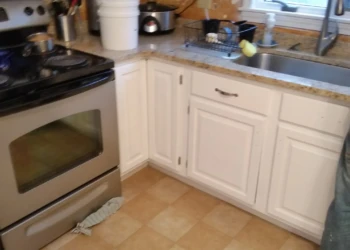 White painted kitchen cabinets surrounding stainless steel oven and sink area, part of cabinet refinishing in Westford