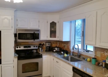 White painted kitchen cabinets with raised panel doors surrounding a stainless steel oven and microwave in a Westford kitchen