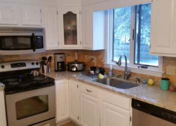 Kitchen featuring white cabinets, granite countertop, stainless steel stove, microwave, dishwasher, and window