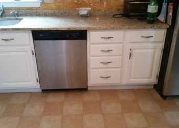 White painted kitchen cabinets under granite countertop in Westford kitchen with stainless steel dishwasher and refrigerator