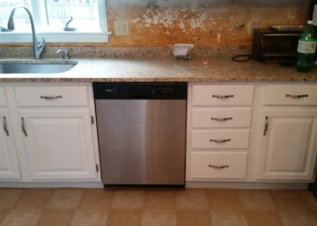 Kitchen cabinets painted white around stainless steel dishwasher under countertop in Westford MA kitchen