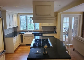 Refinished kitchen cabinets and island in Benjamin Moore Capitol White with black countertops in a Weston MA home