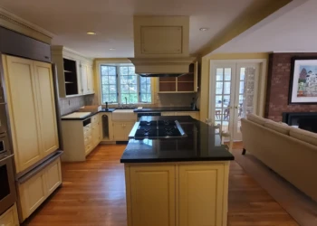 Kitchen with refinished cream-colored cabinets and black granite countertops in a Weston MA home