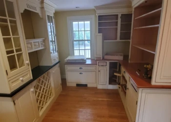Interior view of custom cream-colored cabinetry featuring glass doors, wine racks, and wooden countertops in Weston kitchen