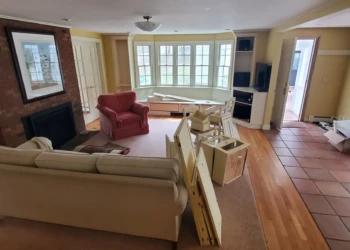 Interior of a living room in Weston with furniture, a brick fireplace, and construction materials for remodeling