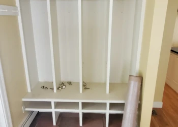 White built-in closet storage unit with cubby shelves and hooks in a home entryway with tiled floor in Weston MA