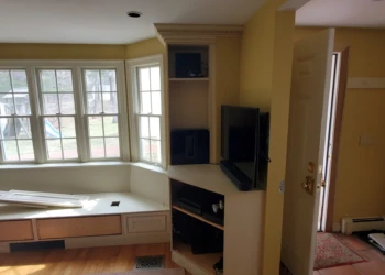 Built-in corner media unit and bay window bench seating with multiple windows in a Weston Massachusetts home