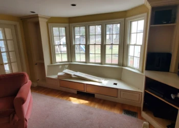 Cozy built-in window seat with storage drawers beneath and entertainment cabinet with TV in Weston MA living area