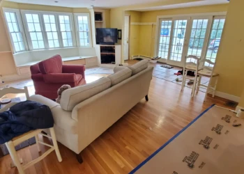Open living room in Weston MA featuring hardwood flooring, bay window seating, and a red armchair