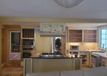 Kitchen interior showing cabinets refinished in distressed white with black countertops in Weston MA home