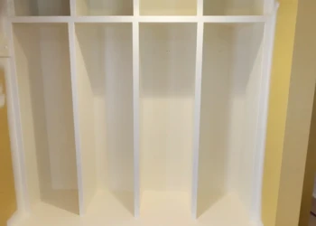 White custom built-in closet with vertical compartments and lower cubbies under ceiling light in Weston MA project